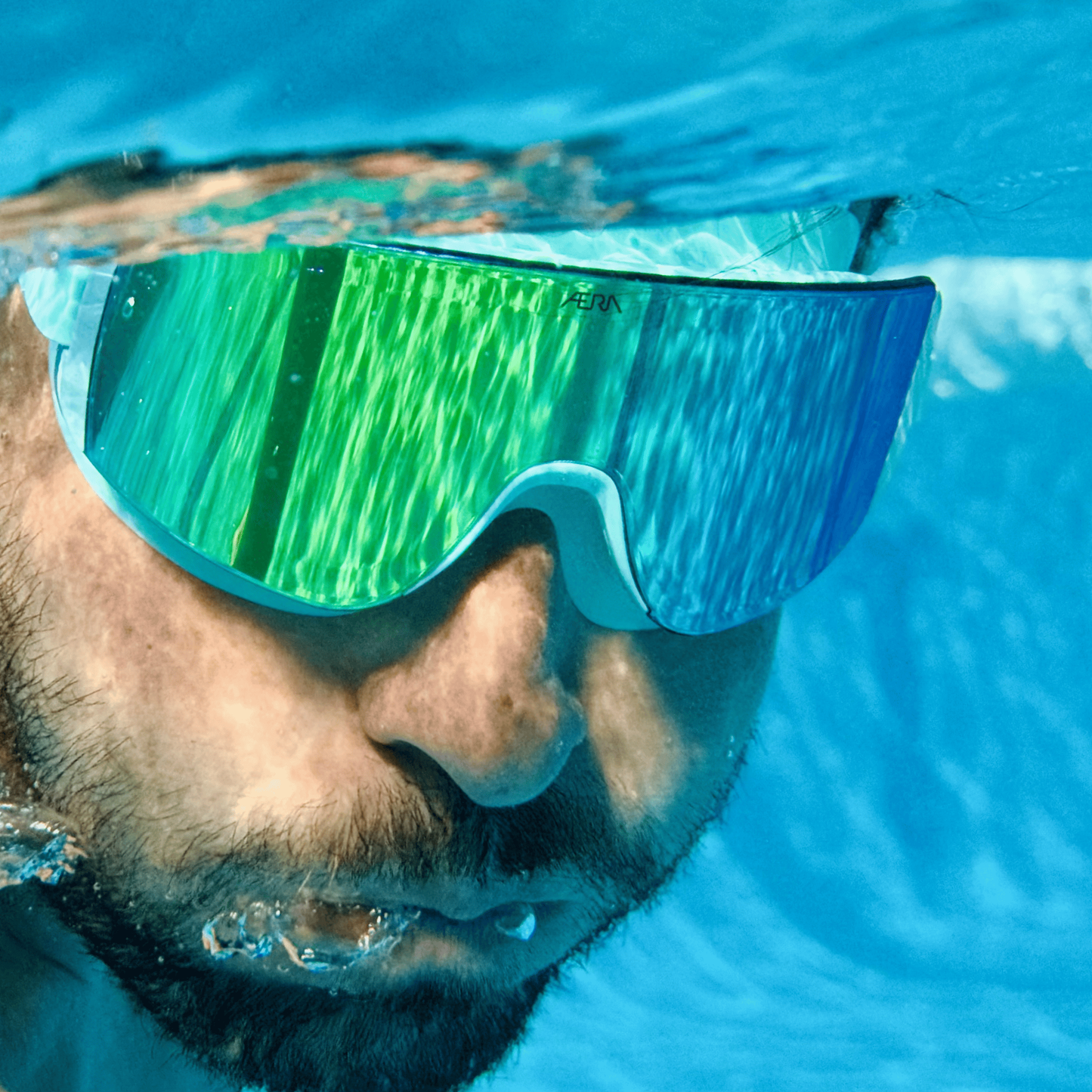 Male swimmer underwater wearing AERA Sports Emerald Lens