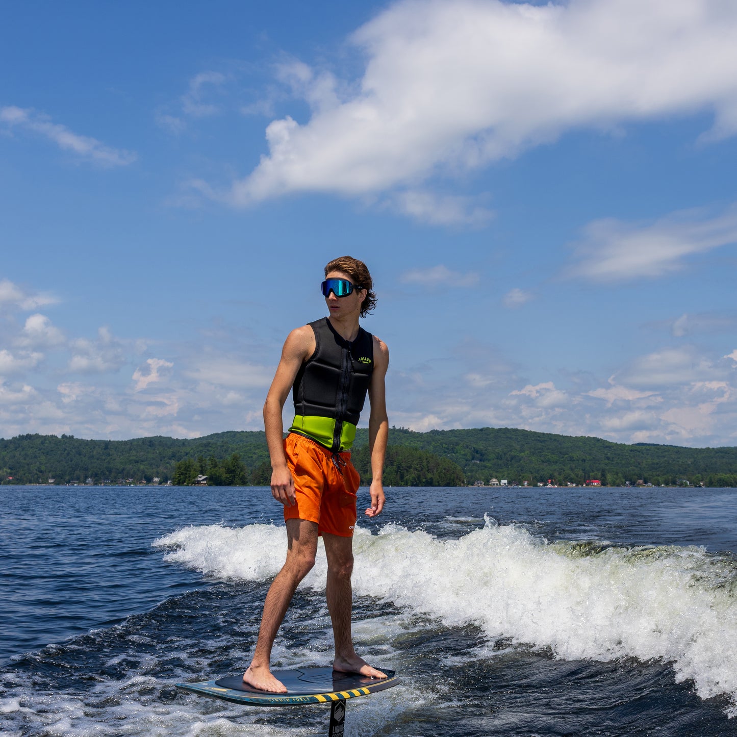Person on a stand-up paddleboard on a lake with a blue sky and green hills in the background wearing Blue Steel AERAs