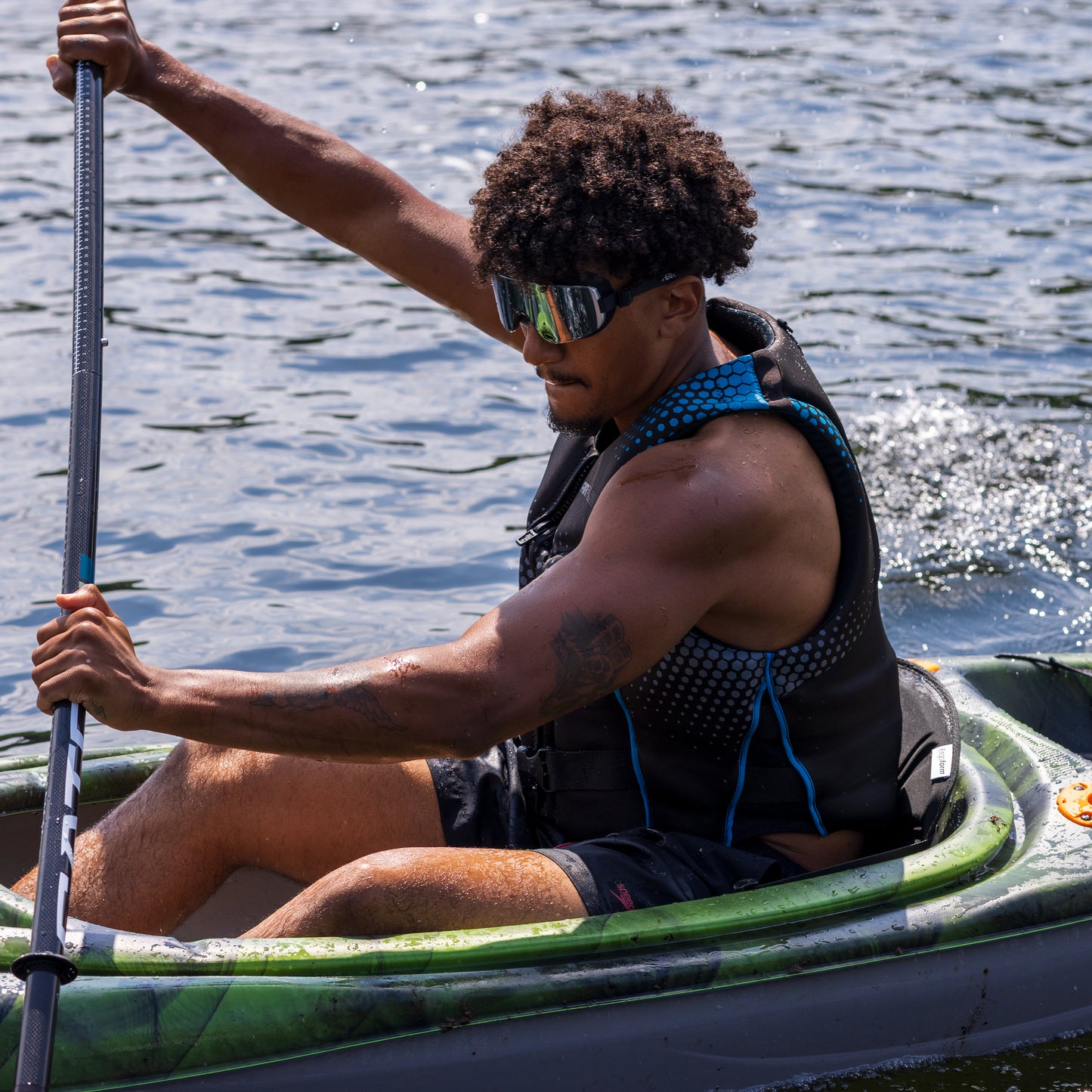 Man paddling a kayak on calm water wearing Black Mirror AERA swim goggles for clear vision and glare reduction