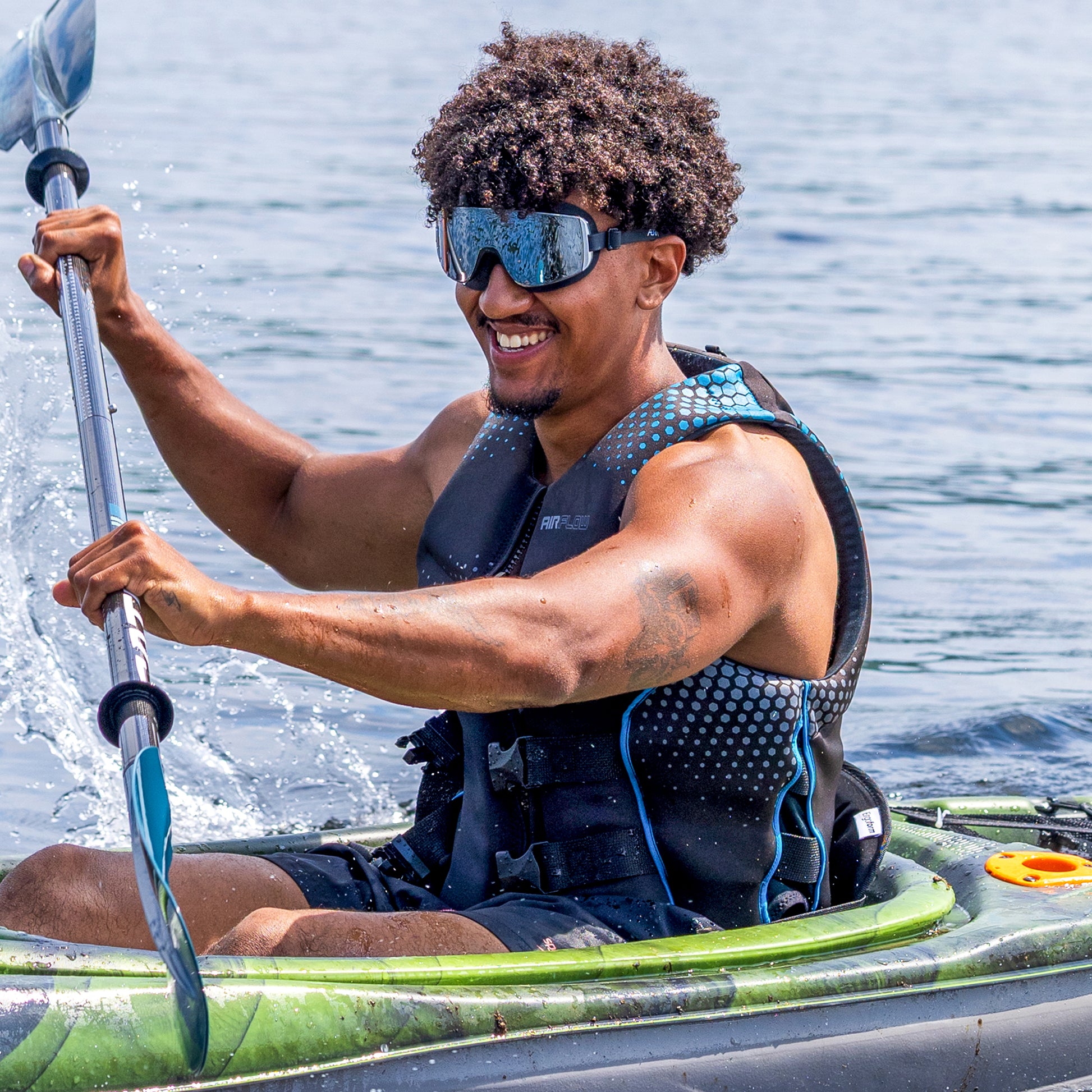 Man paddling a kayak wearing ÆRA Black Mirror performance swimming goggles with UV protection on open water
