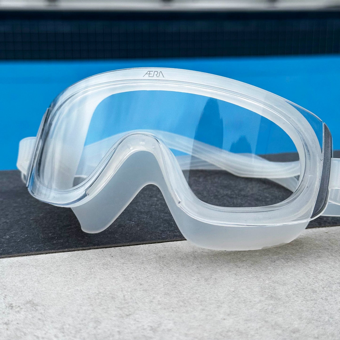 Clear swim goggles with a blue pool background