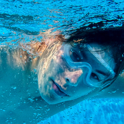 Person swimming underwater wearing a clear swimming goggles
