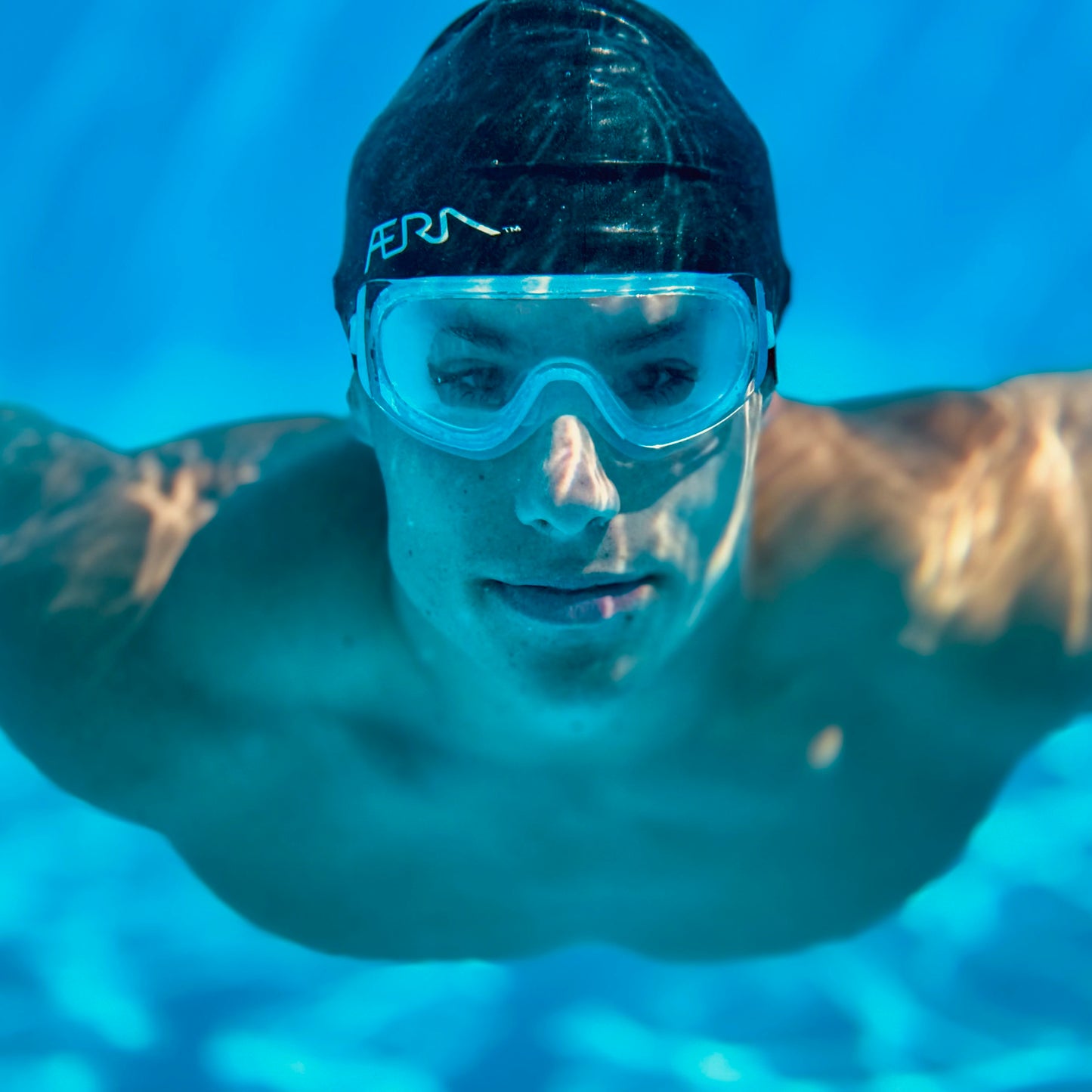 Person wearing a swim cap and clear goggles underwater