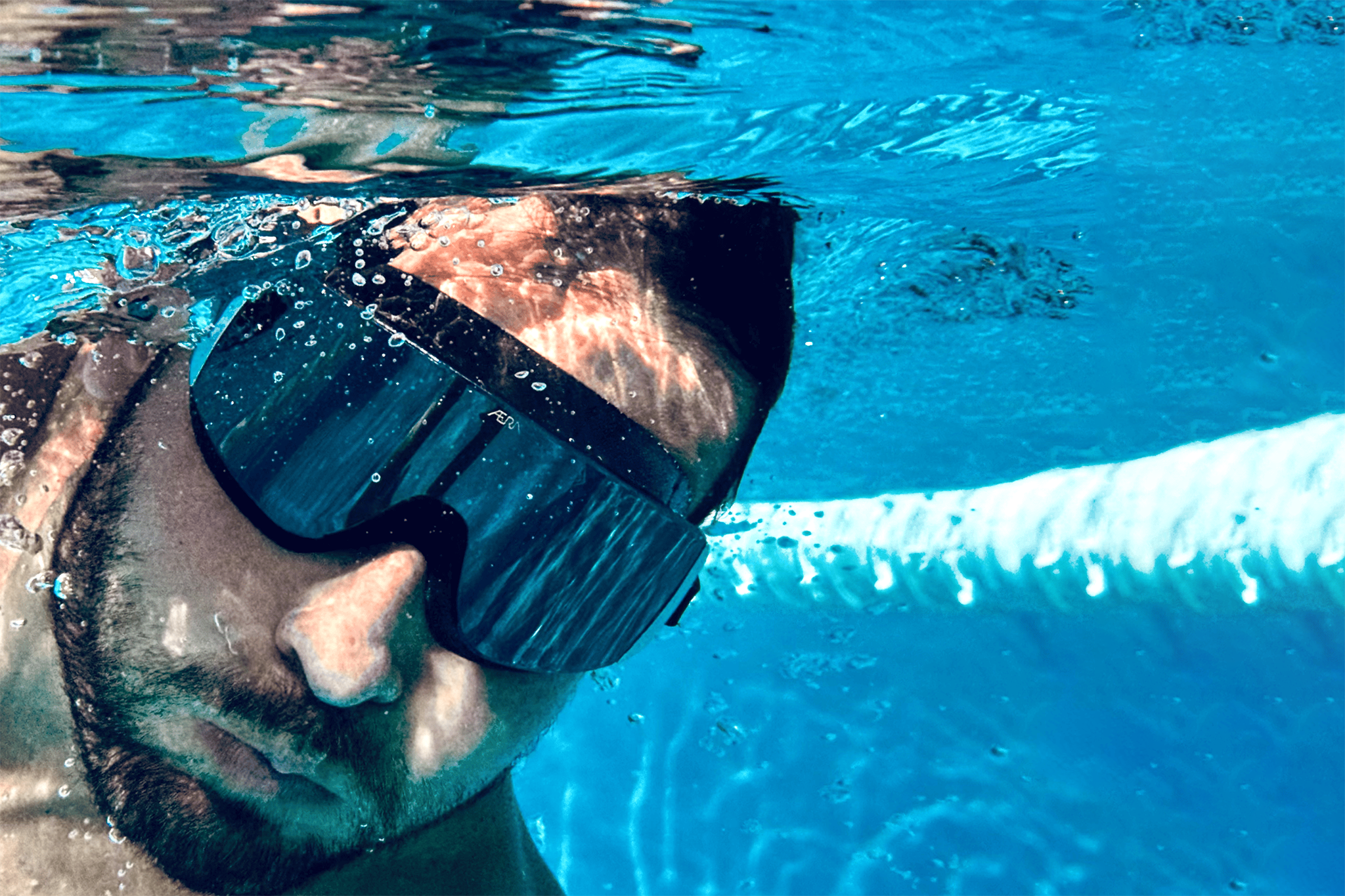 Male swimmer underwater with AERA Sports goggles, highlighting the importance of maintaining peak performance and clarity during training
