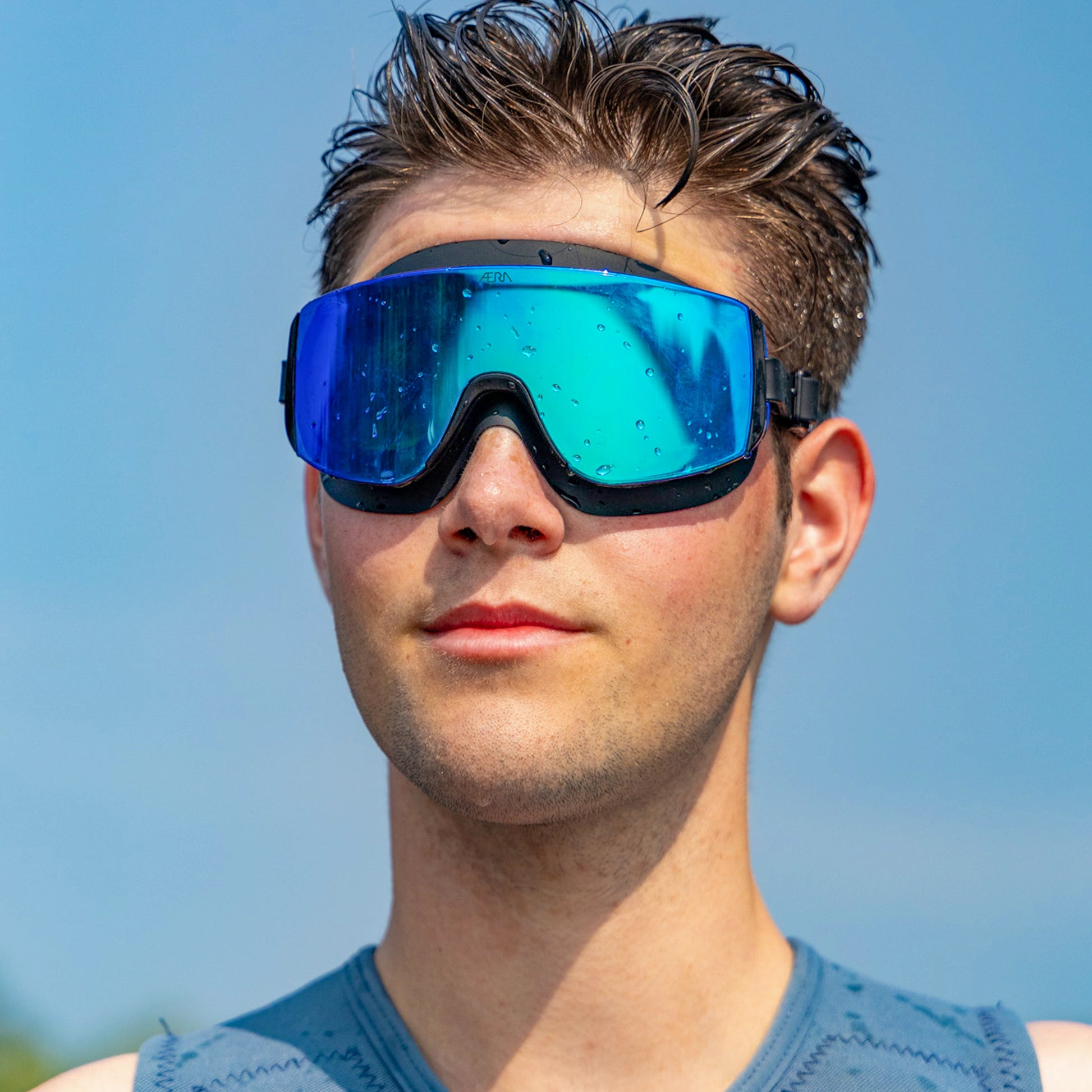 Person wearing blue reflective goggles against a clear sky