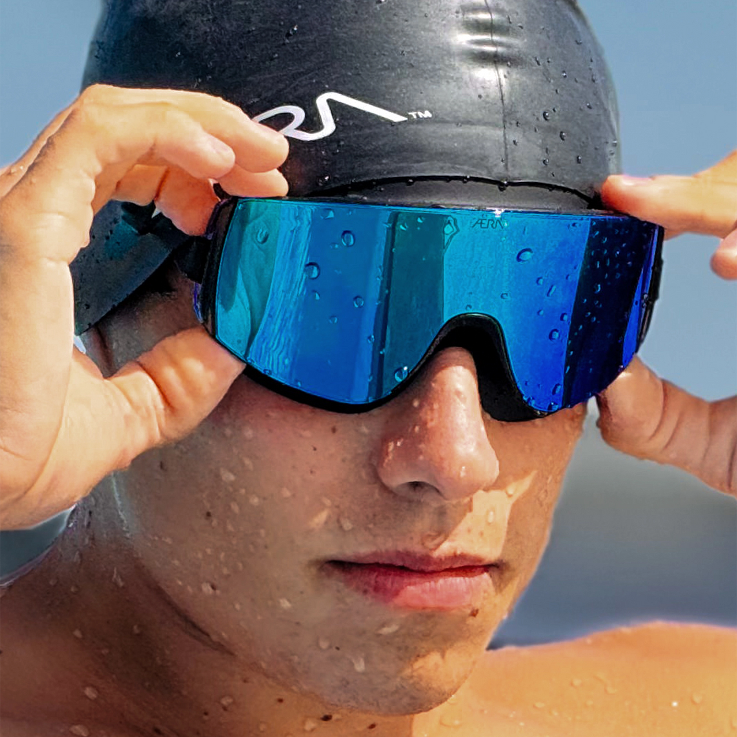Person wearing a swim cap and blue goggles with a blurred background