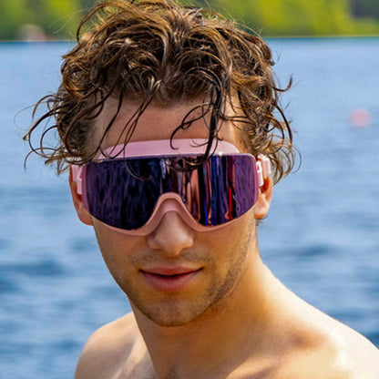 “Man wearing ÆRA Blushwave polarized swimming goggles with a lake and trees in the background, featuring anti-fog lenses and UV protection for adults