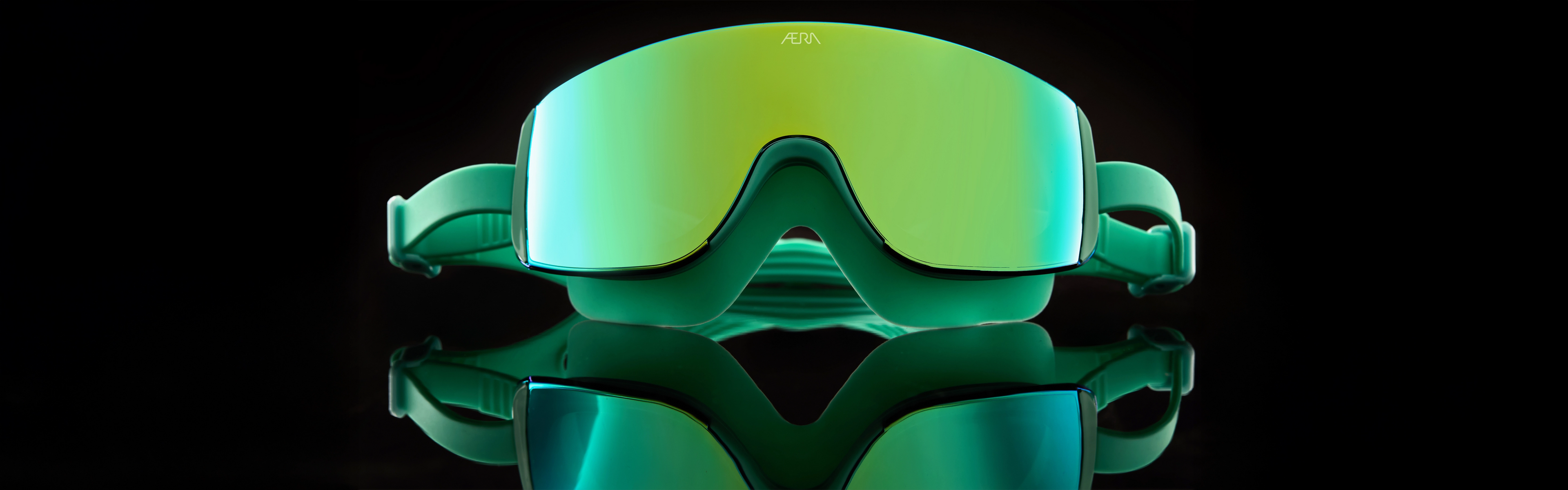 Green goggles with a reflective surface on a black background