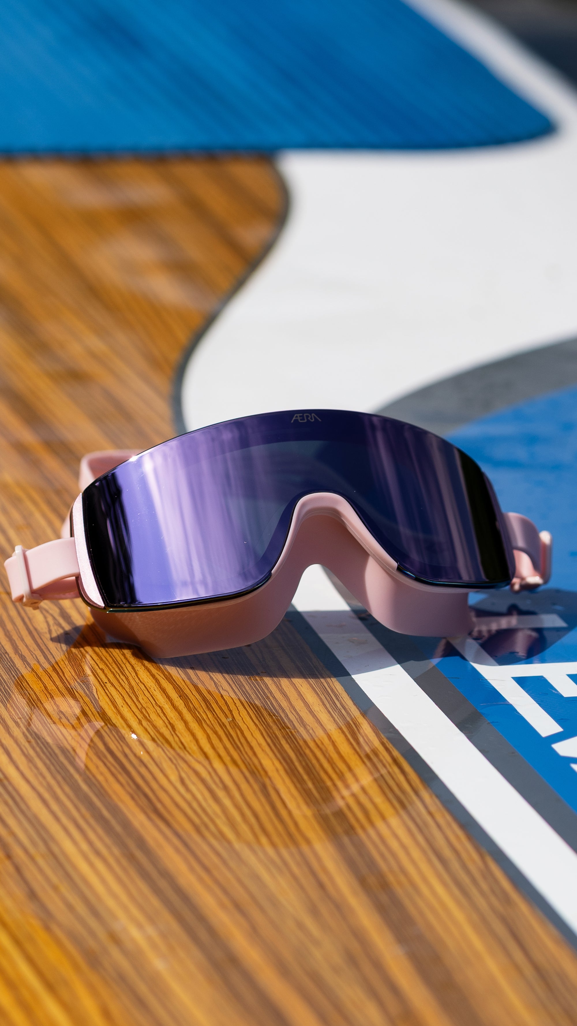 Sunglasses with a reflective purple lens on a wooden surface